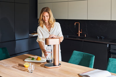 A woman using a copper Mysoda Ruby in a black kitchen